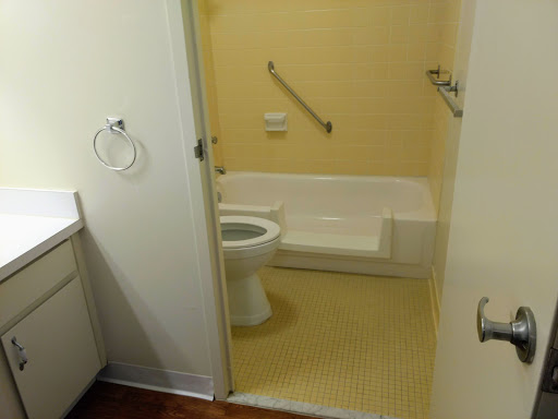 A simple and clean bathroom featuring a toilet and bathtub with yellow walls.