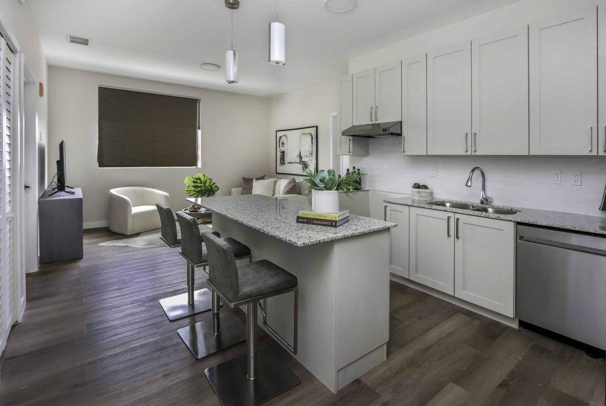 A modern kitchen with sleek white cabinets, a central island with bar stools, and contemporary pendant lighting.