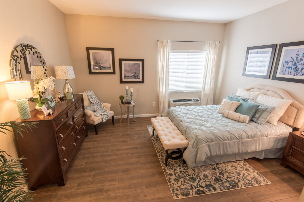 A cozy bedroom with stylish decor, featuring a neatly made bed, wooden dresser, and soft lighting.