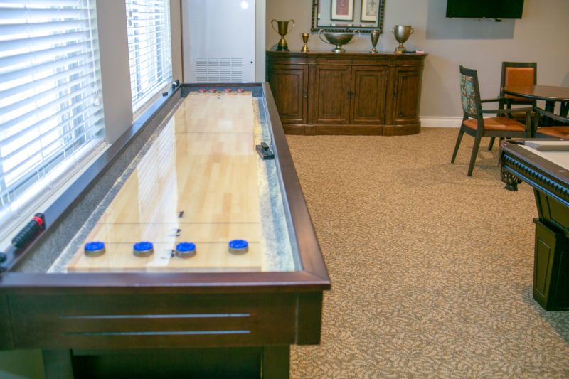 A shuffleboard table in a well-furnished game room.