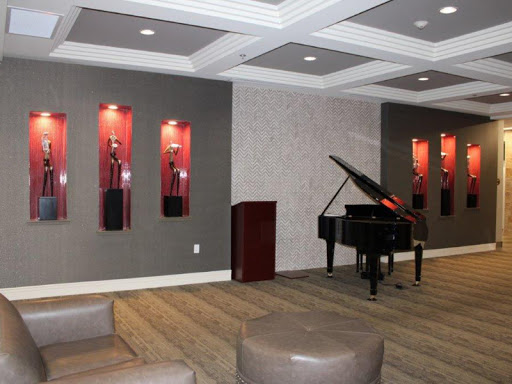 A stylish lounge area featuring a grand piano and decorative wall displays of awards.
