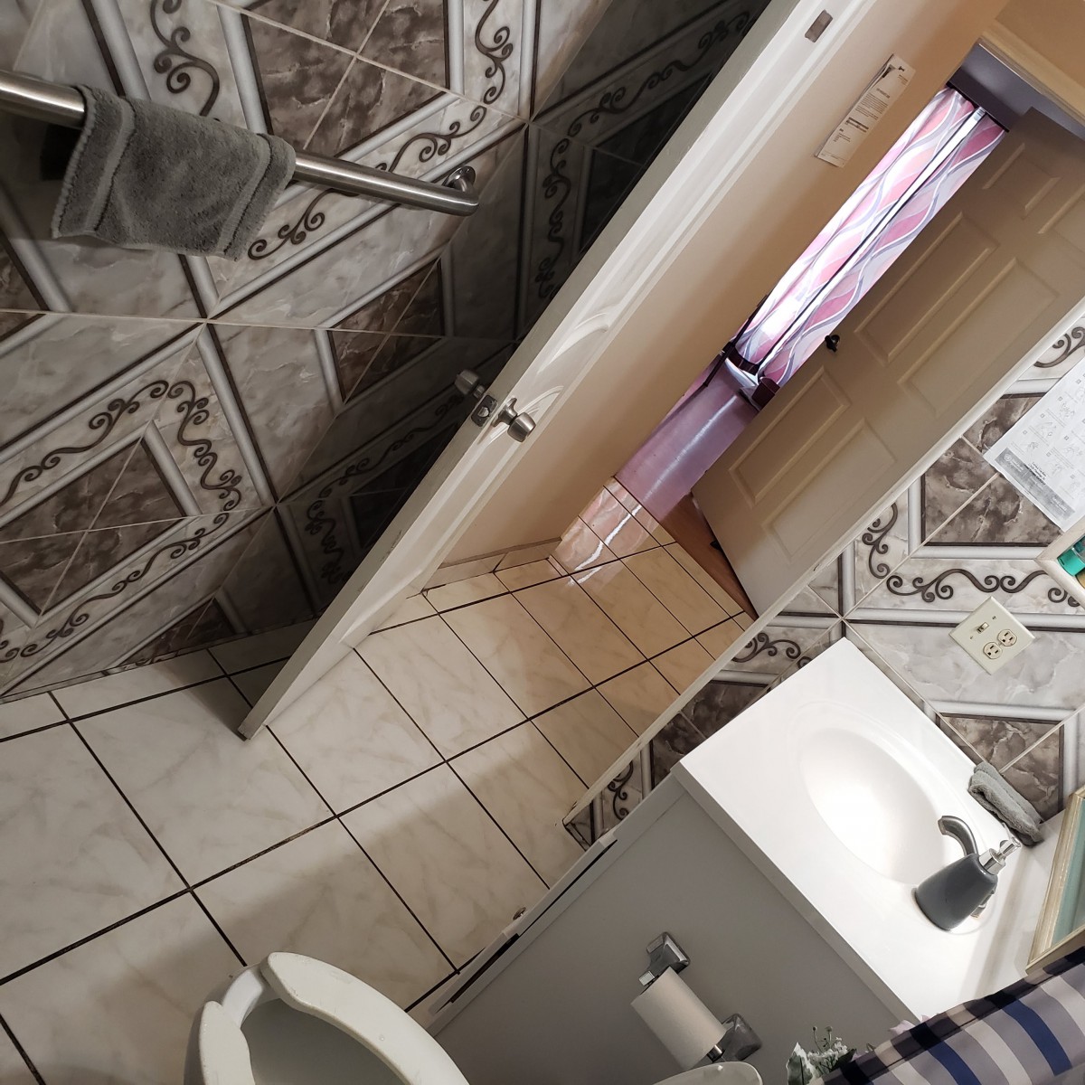 A tiled bathroom with a sink, toilet, and door slightly ajar.