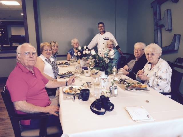 A group of seniors enjoying a meal together at a dining table.