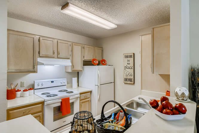 A cozy kitchen with wooden cabinets, a white stove and refrigerator, and decorative items on the countertop.