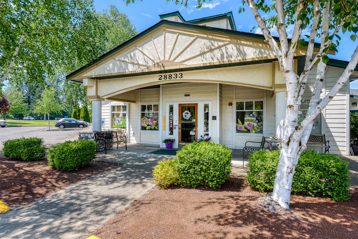 A welcoming building entrance surrounded by trees and well-maintained landscaping.