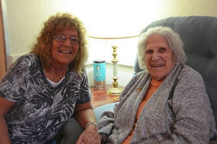 Two women smiling while seated in a comfortable living room setting.