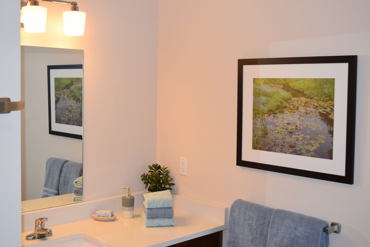 A well-decorated bathroom with a mirror, artwork, and neatly arranged accessories.