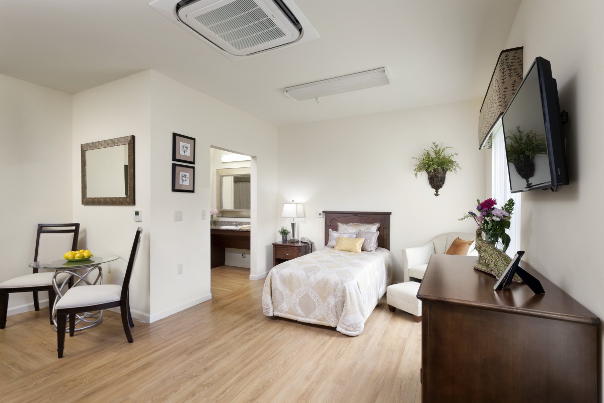 A minimalist bedroom with a single bed, wooden floors, and tasteful decorations.