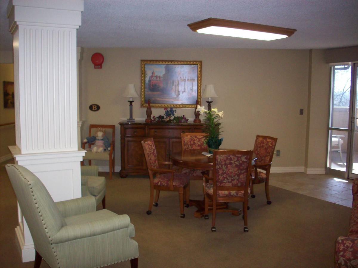 A cozy room with a table and chairs, decorated with artwork and lamps.