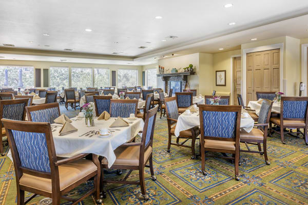 A well-arranged dining room with neatly set tables and chairs in a formal setting.