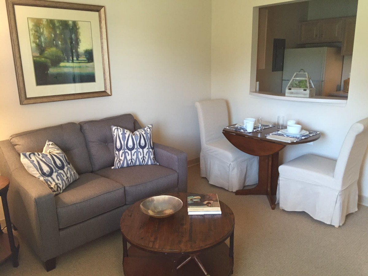 A cozy living room with a comfortable sofa, round coffee table, and adjacent dining area.