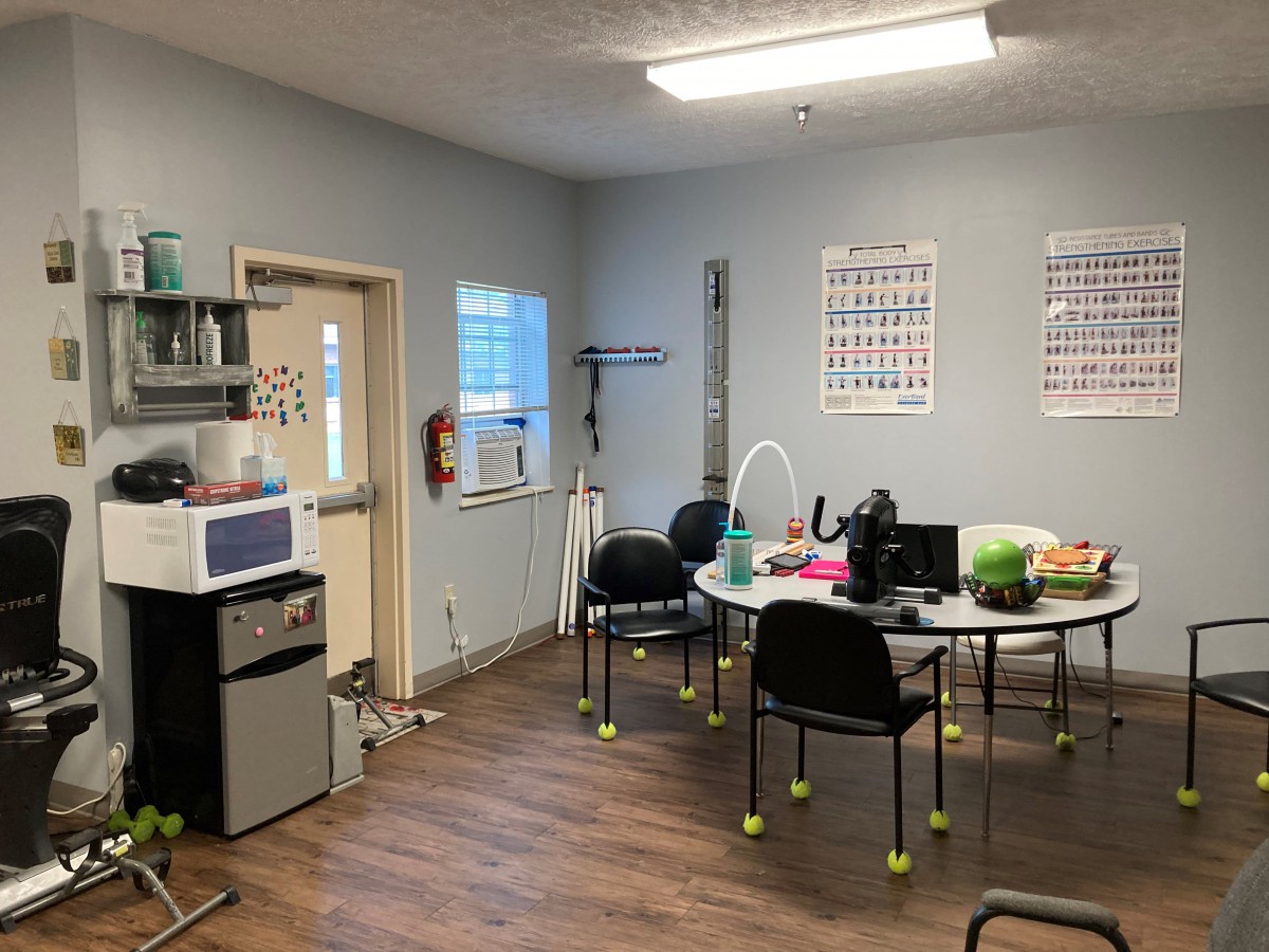 A clinic office room with chairs, a table, and medical equipment.