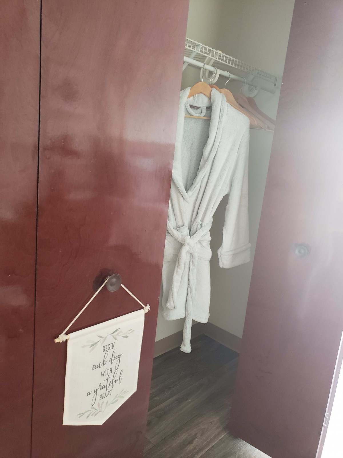 A bathrobe hanging in a hotel room closet with a sign on the door.