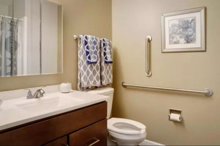 A well-organized bathroom featuring a toilet, sink, and towel rack.