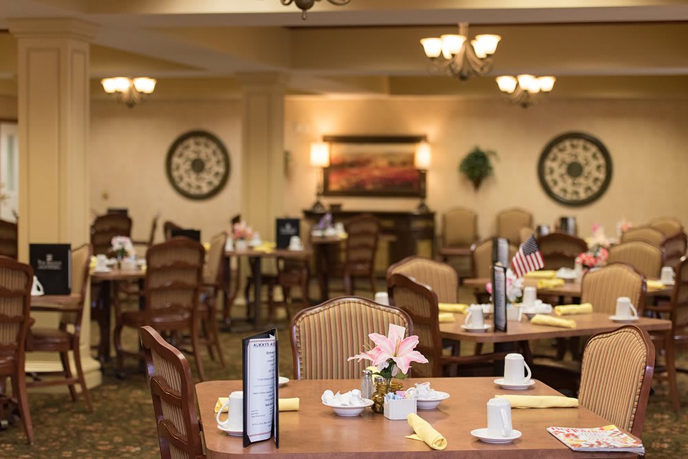 A well-decorated dining area with neatly arranged tables and chairs, featuring elegant decor and table settings.