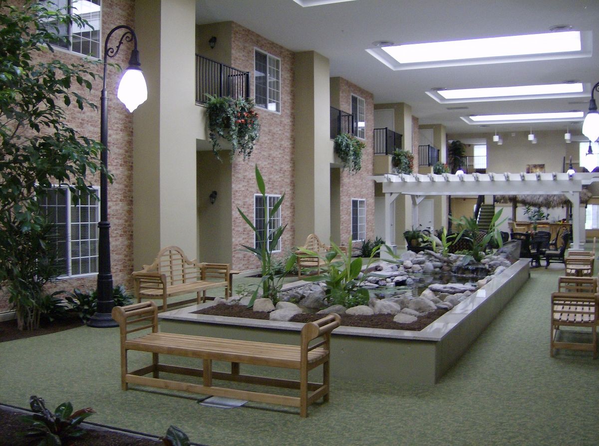 An indoor garden featuring plants, benches, and skylights creates a serene atmosphere.