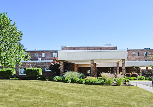 A well-maintained building surrounded by lush greenery under a clear blue sky.