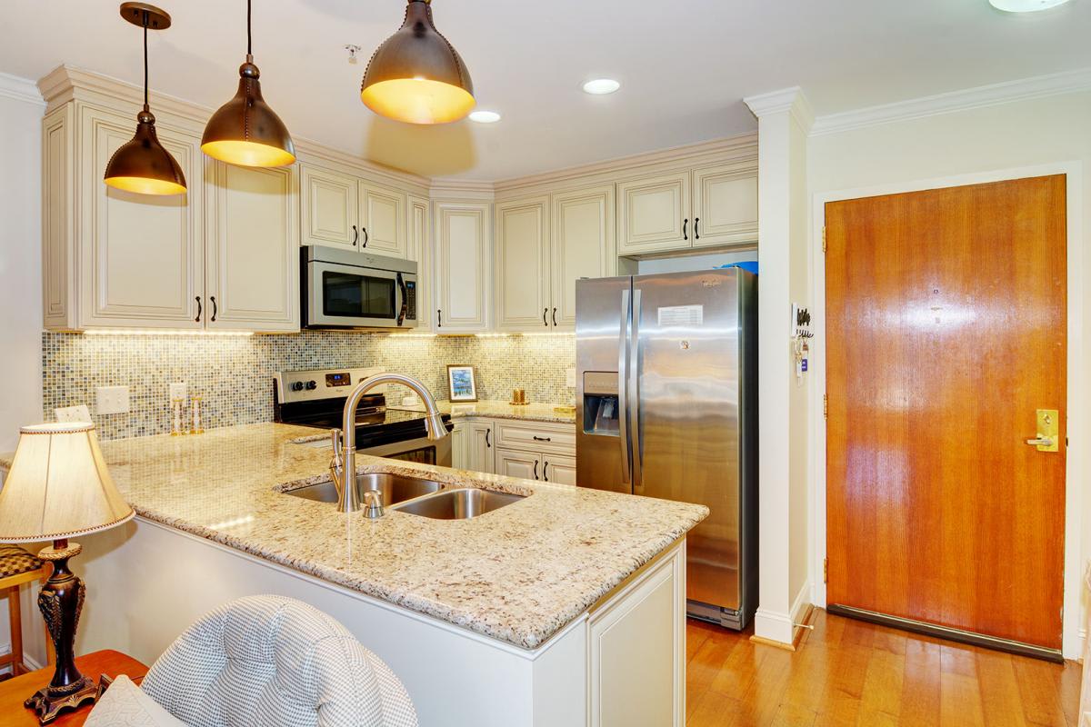 A modern kitchen featuring stainless steel appliances, granite countertops, and pendant lighting over an island sink.