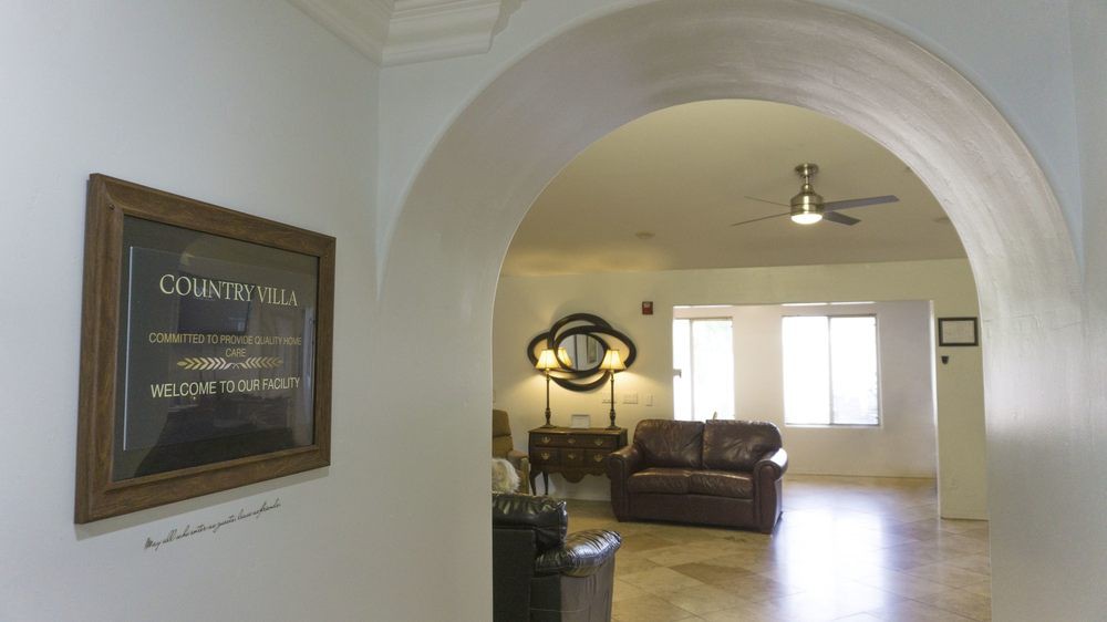 A view of a cozy living room through an archway, featuring a sofa, lamp, and wall art.