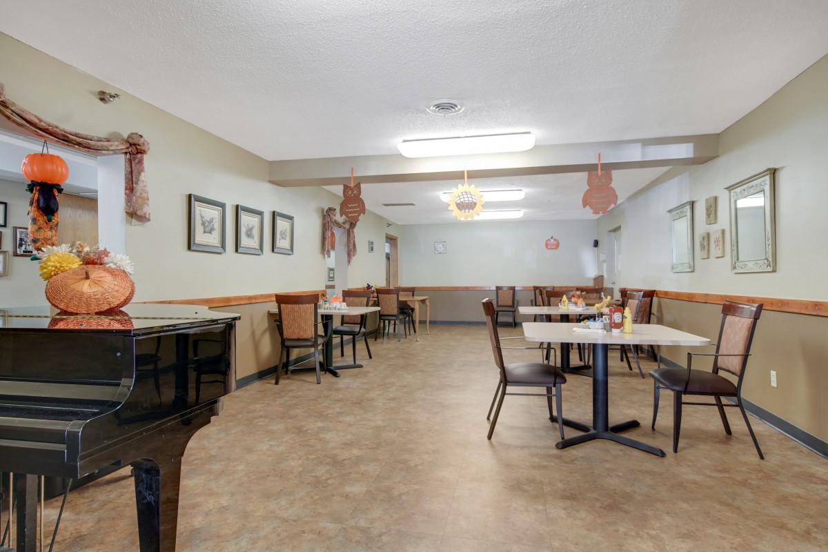 An empty dining area with neatly arranged tables and chairs, decorated with wall art and pendant lights.