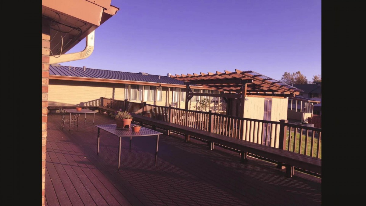 A spacious outdoor deck with a table and benches under a pergola.