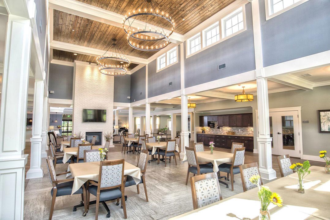 A spacious and bright restaurant interior with elegant chandeliers and neatly arranged tables.