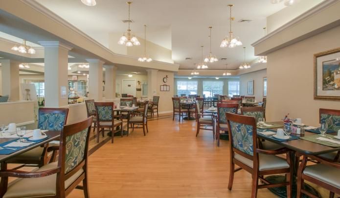 A spacious dining area with neatly arranged tables and chairs, well-lit by overhead lighting.