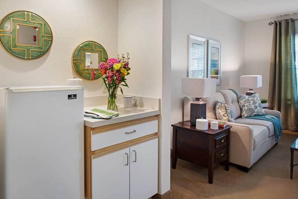 A cozy living area featuring a comfortable sofa, decorative mirrors, fresh flowers, and ambient lighting.
