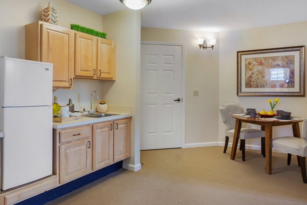 A cozy apartment kitchen with wooden cabinets, a sink, and a small dining area.