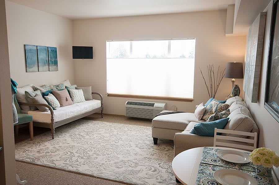A cozy and modern living room with light-colored furniture and large window.