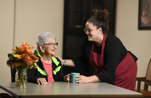 A caregiver interacts warmly with an elderly woman, fostering a sense of connection and support.