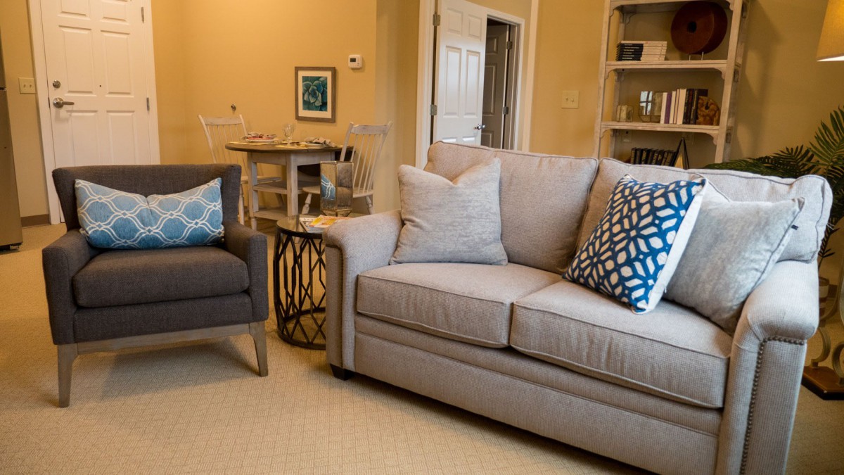 A cozy living room with a beige sofa and armchair, adorned with decorative pillows.
