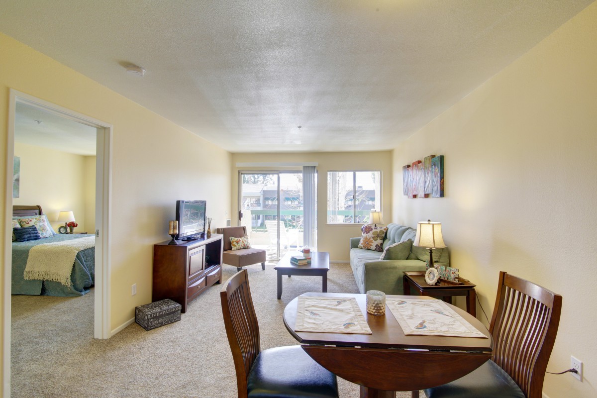 A cozy living room interior with a dining table, sofa, and television.