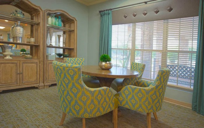 A cozy dining room with patterned chairs and a round table near large windows.