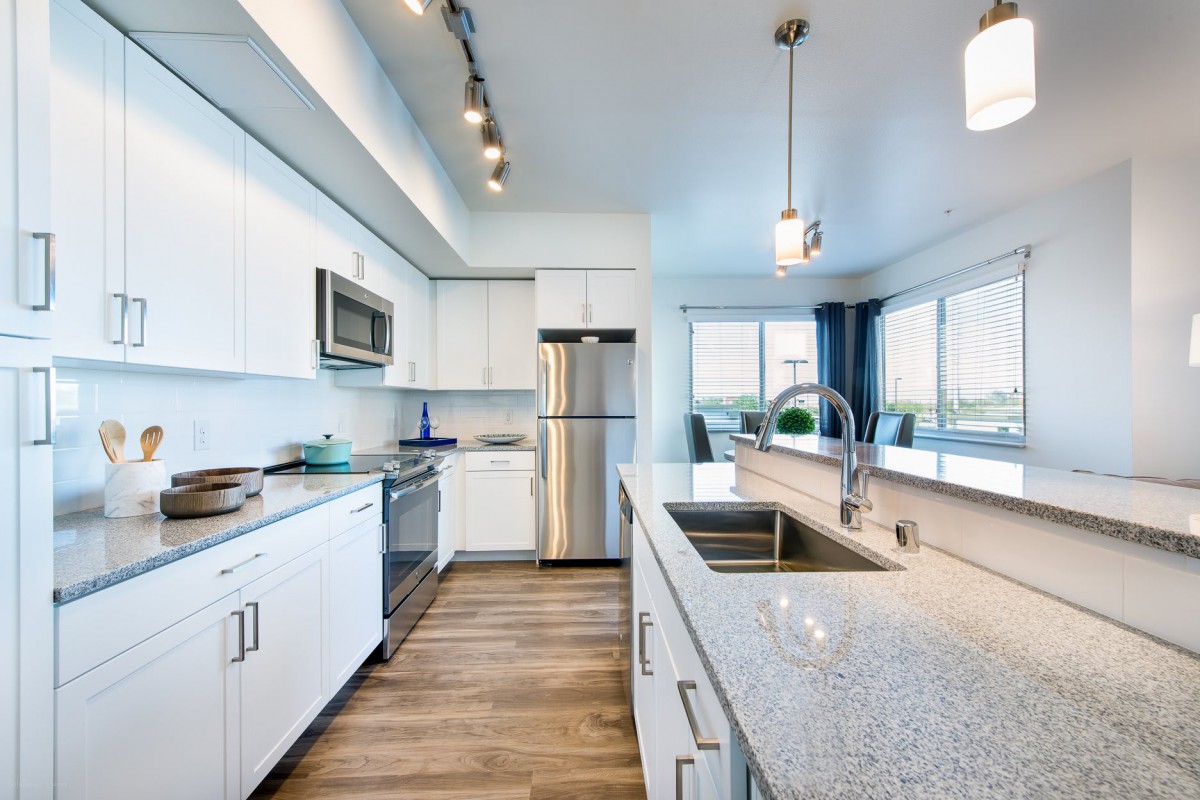 A modern kitchen with stainless steel appliances, white cabinets, and granite countertops.