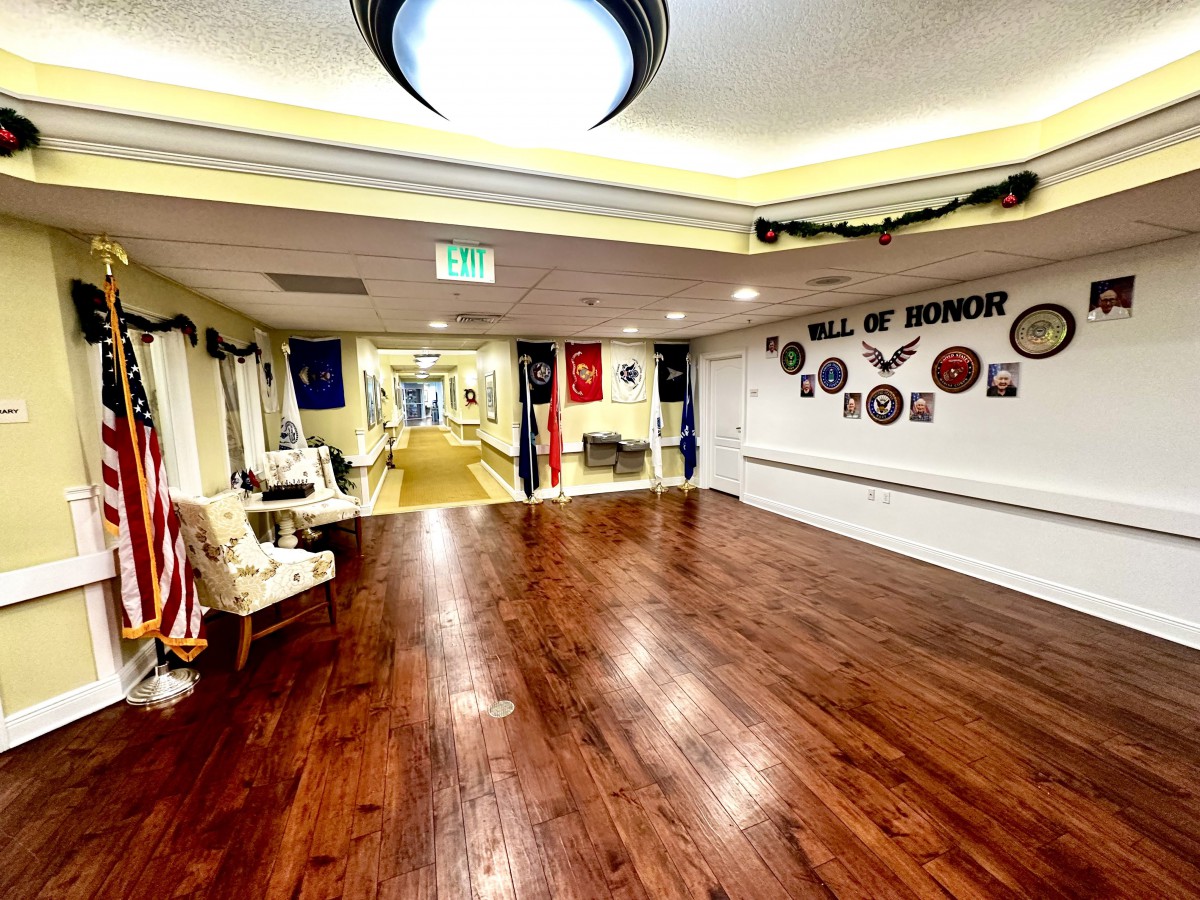 A well-lit interior hallway featuring wooden floors, decorated walls, and comfortable seating areas.