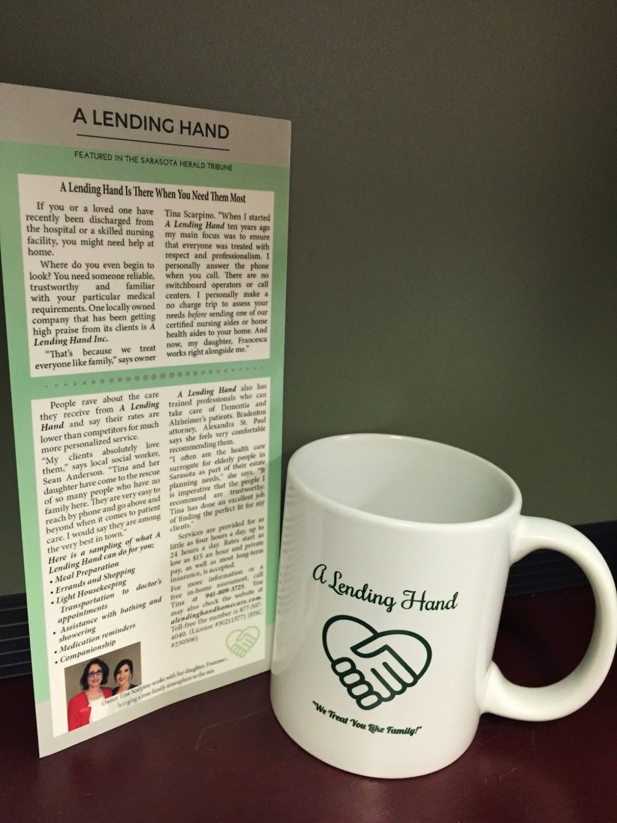 A ceramic mug with 'A Lending Hand' printed on it sits beside a newsletter.