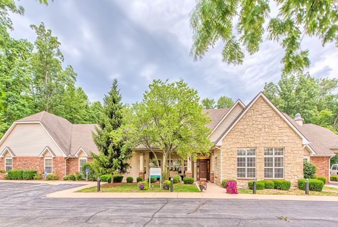 A suburban house with a well-maintained garden and trees lining the driveway.