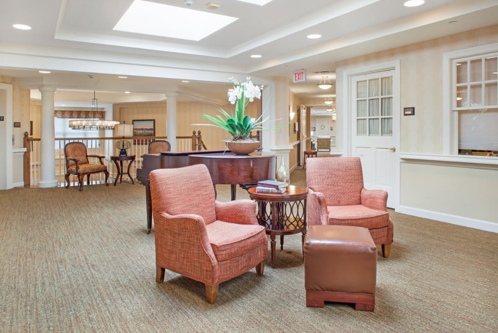 A cozy lounge area featuring comfortable armchairs, a grand piano, and soft lighting.