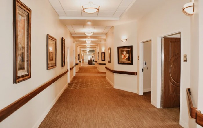 A well-lit hallway adorned with paintings on the walls.