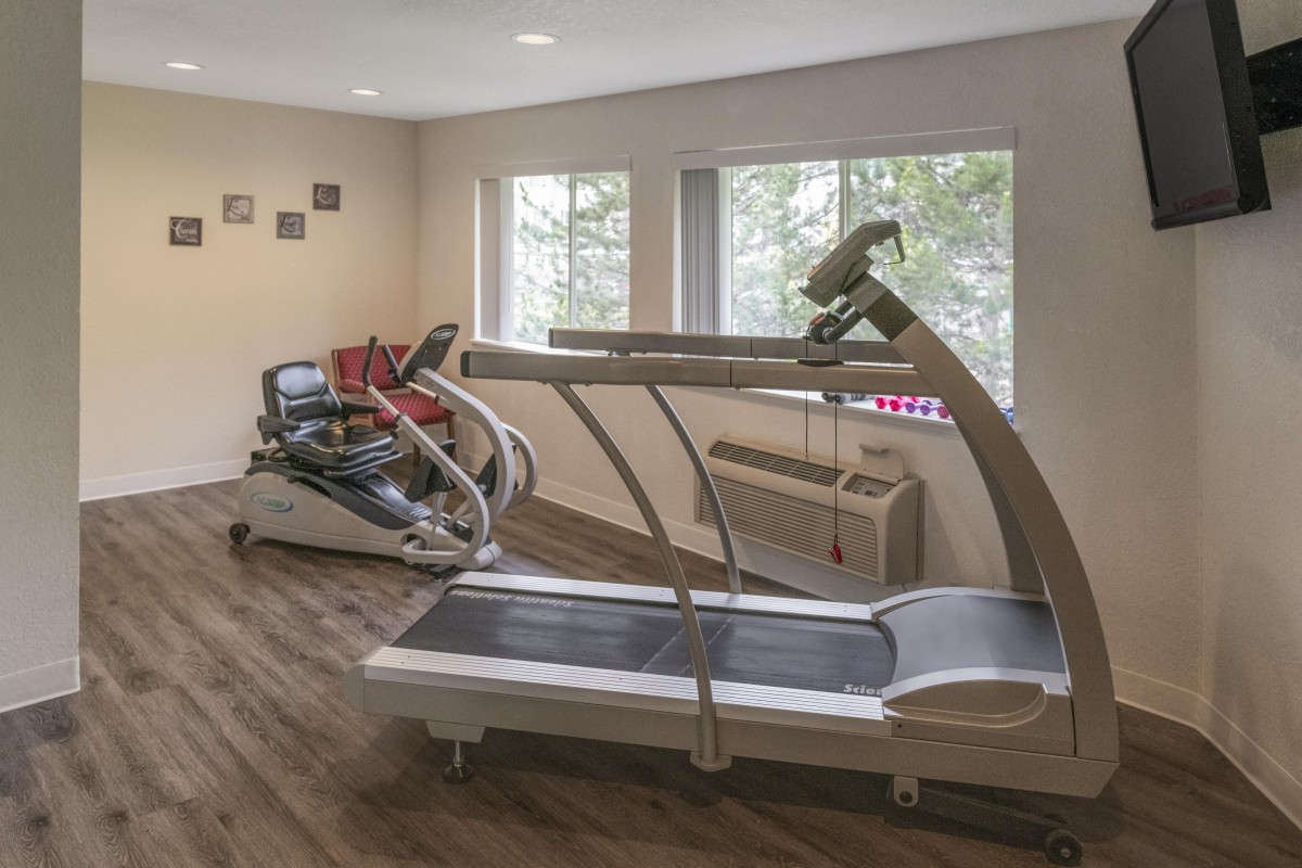 A small gym room featuring a treadmill and other exercise equipment.