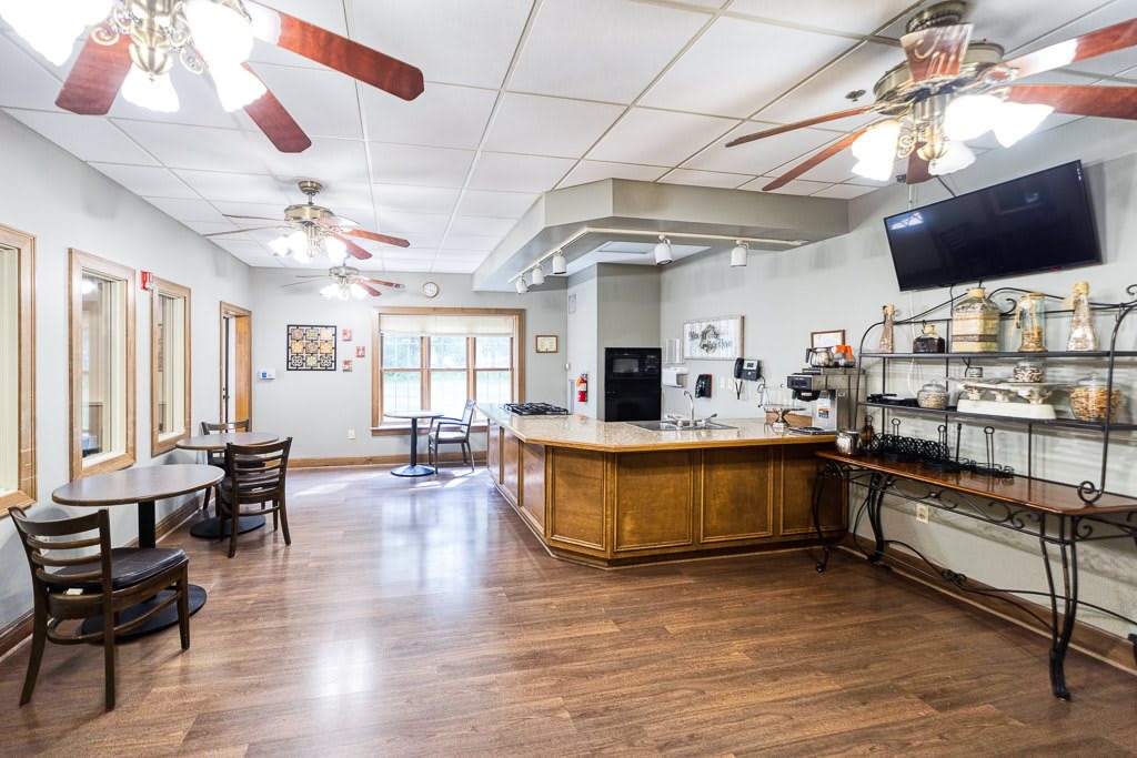 A spacious kitchen and bar area with wooden flooring and ceiling fans.