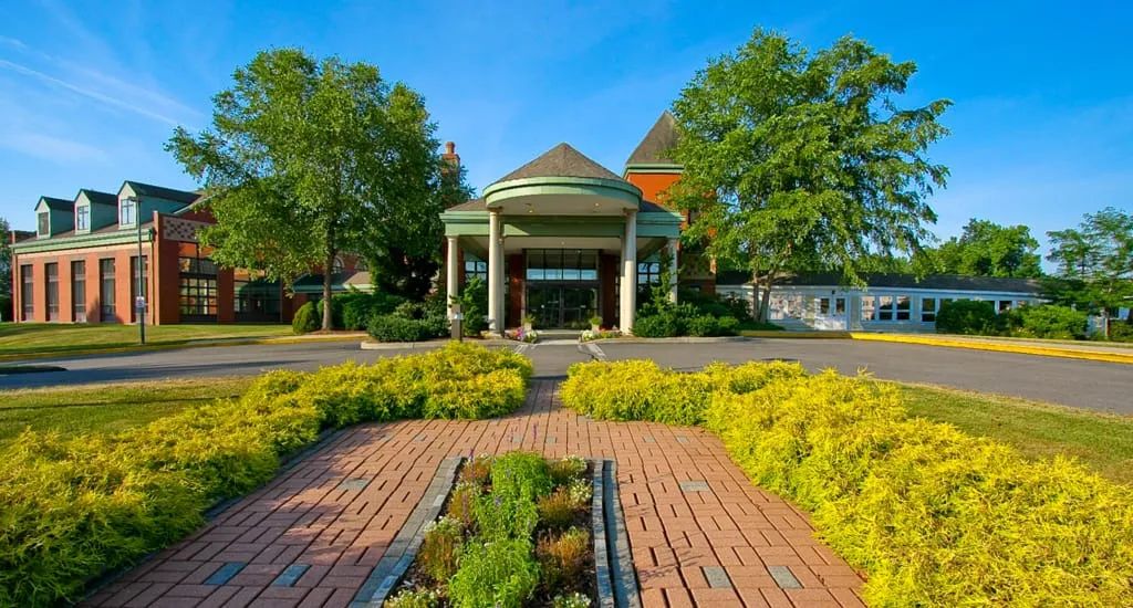 A beautiful entrance to a building with lush landscaping and a brick pathway.