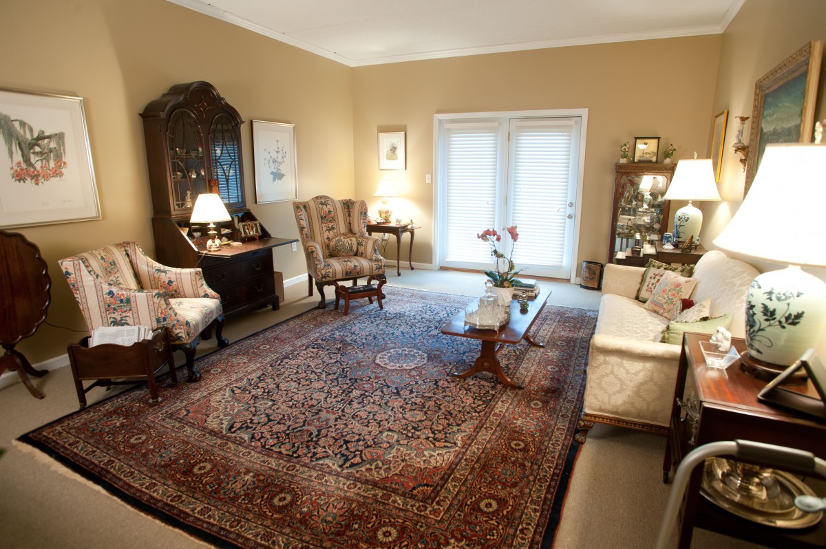 A traditionally decorated living room featuring antique furniture and a large patterned carpet.