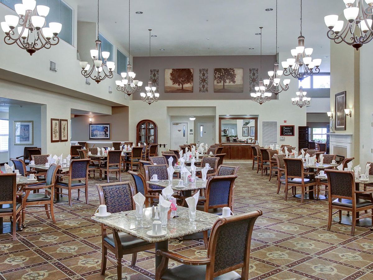 A spacious dining area with elegant chandeliers and neatly arranged tables.