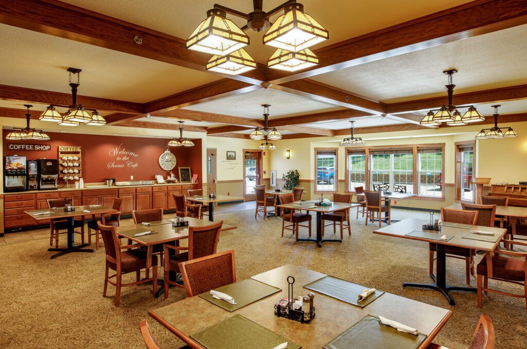 A spacious and elegantly designed restaurant dining room featuring wooden beams, ample tables and chairs, and large windows that bring in natural light.