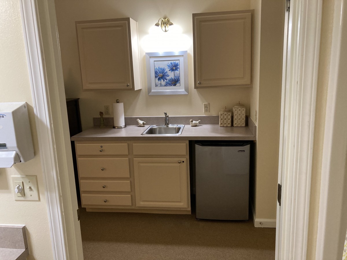 A small kitchenette featuring a sink, mini fridge, and cabinets.