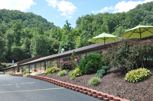 A scenic view of a building surrounded by lush greenery and colorful flowers, featuring an outdoor umbrella for shade.