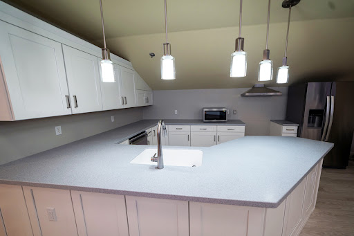 A modern kitchen featuring white cabinets, a sleek countertop, and stylish pendant lighting.