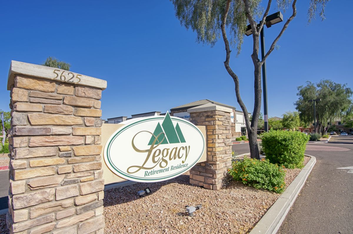 Entrance sign for Legacy property with landscaping and brick wall.